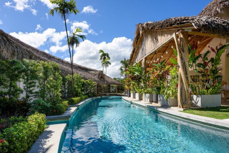 Piscina exterior rodeada de vegetación tropical en Takuma Boutik Hotel con cabaña de techo de paja