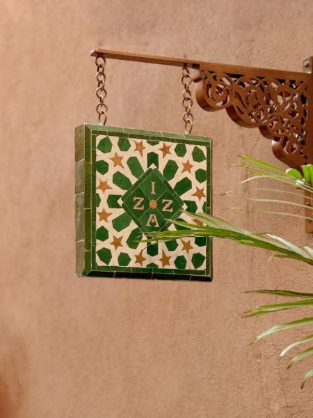 Cartel de mosaico árabe con el logotipo del hotel IZZA Marrakech en la entrada del riad