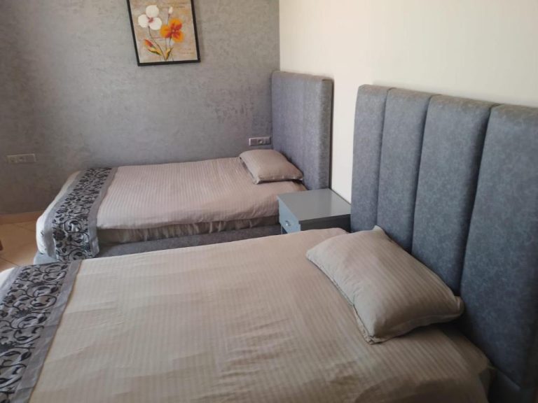 Habitación twin con dos camas y cabecero tapizado gris en Appart Hôtel Founty Beach