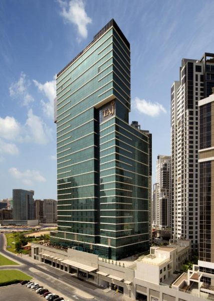 Vista exterior de la torre de cristal del Taj Dubai con su imponente fachada verde en Dubai Marina