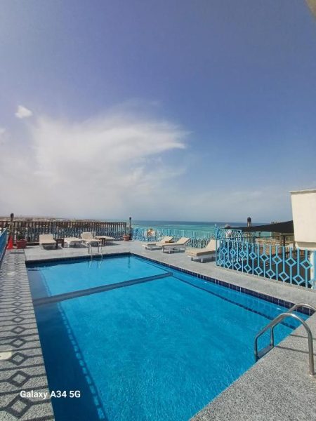 Piscina exterior con vistas al Mar Rojo y tumbonas en Palm Inn Hotel Hurghada, Egipto