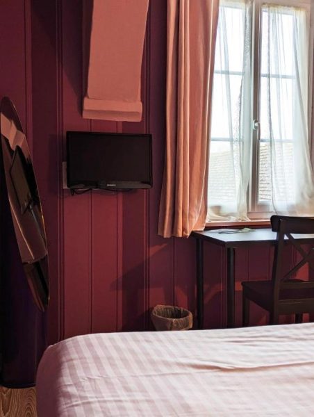 Habitación del Hotel du Saumon en Verneuil sur Avre con televisión, escritorio y ventana con cortinas