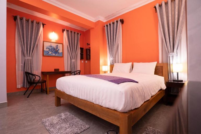 Habitación doble con paredes naranjas y cama de madera en Daun Penh Palace Boutique