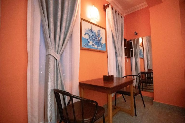 Salón comedor interior con mesa de madera y cortinas grises del Daun Penh Palace Boutique