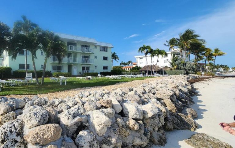 Fachada del hotel Key Colony Beach con jardín, tumbonas y orilla rocosa frente al mar en Florida Keys