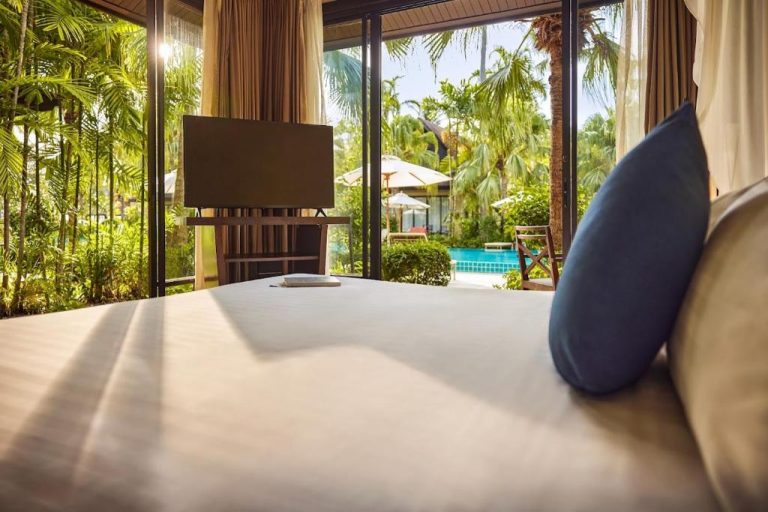 Habitación con cama doble y vistas a la piscina rodeada de palmeras en TUI BLUE The Passage Samui