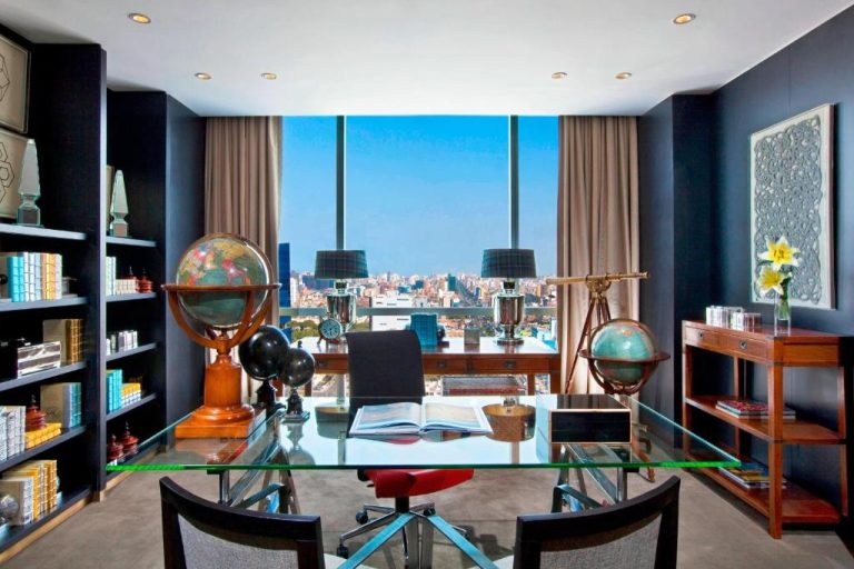 Suite ejecutiva con escritorio de cristal, globos terráqueos y vistas panorámicas de Lima en The Westin Lima Hotel