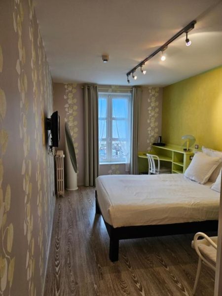 Habitación doble moderna con cama matrimonial y decoración en verde del Hotel du Saumon en Verneuil sur Avre