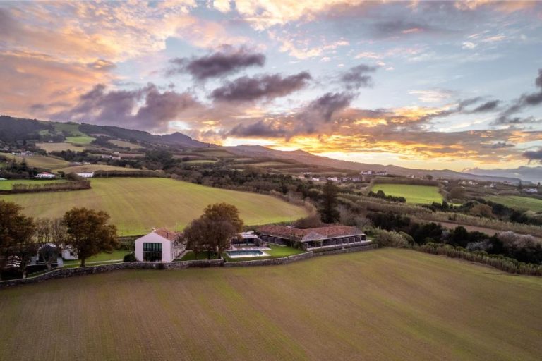 Vista aérea del SENSI Azores Nature and SPA rodeado de campos verdes y montañas al atardecer