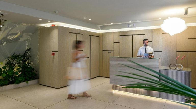 Recepción moderna del Arcadion Hotel con mostrador de madera y personal atendiendo a los huéspedes