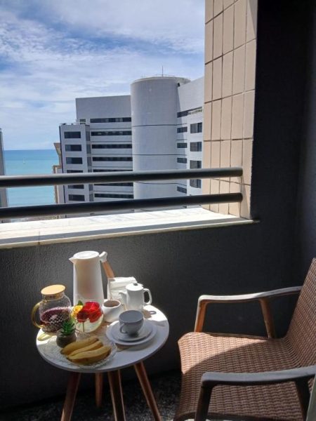 Balcón con desayuno y vista al mar en Flat Saint Martin 1807, con mesa servida y edificios costeros