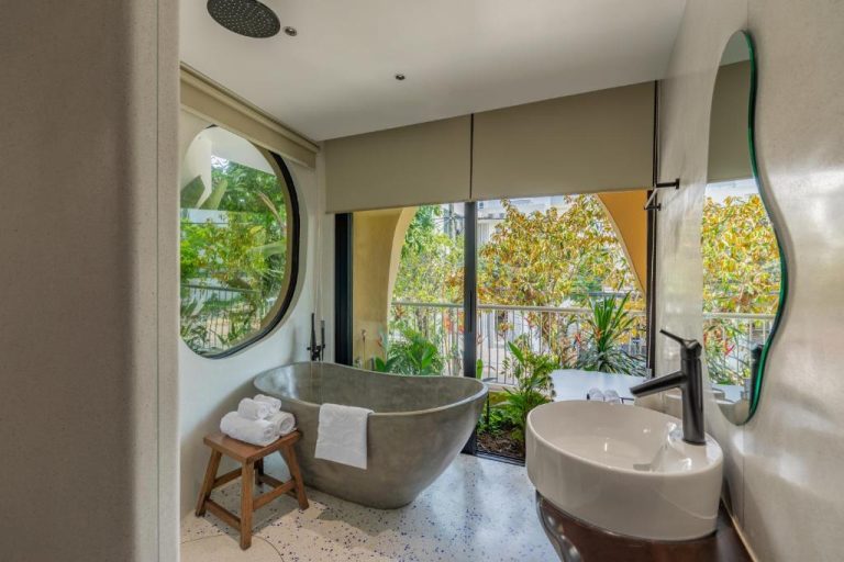 Baño de lujo con bañera exenta de piedra y ventanas con vistas verdes en Saha Casa Boutique Hotel Da Nang