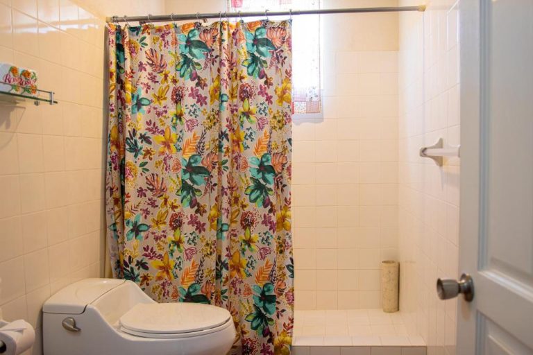 Baño completo con ducha y cortina floral colorida en Best E Villas Prospect St James