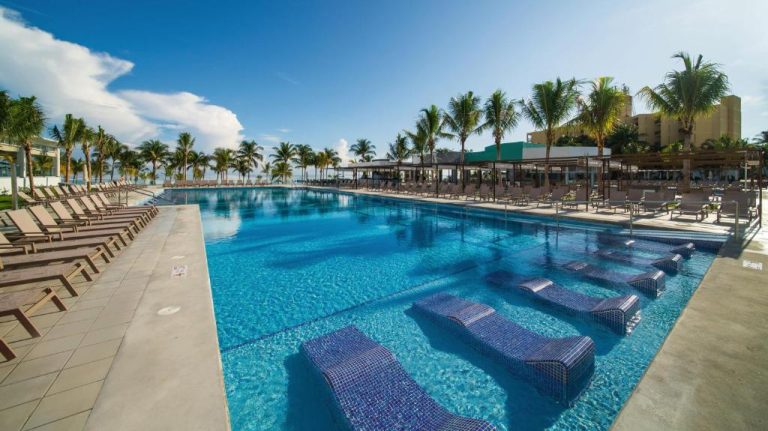 Amplia piscina exterior con tumbonas sumergidas y palmeras del Riu Ocho Rios All Inclusive en Jamaica