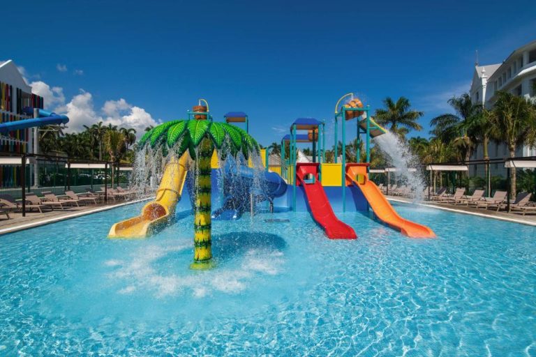 Parque acuático con toboganes de colores y palmera decorativa en la piscina del Riu Ocho Rios All Inclusive