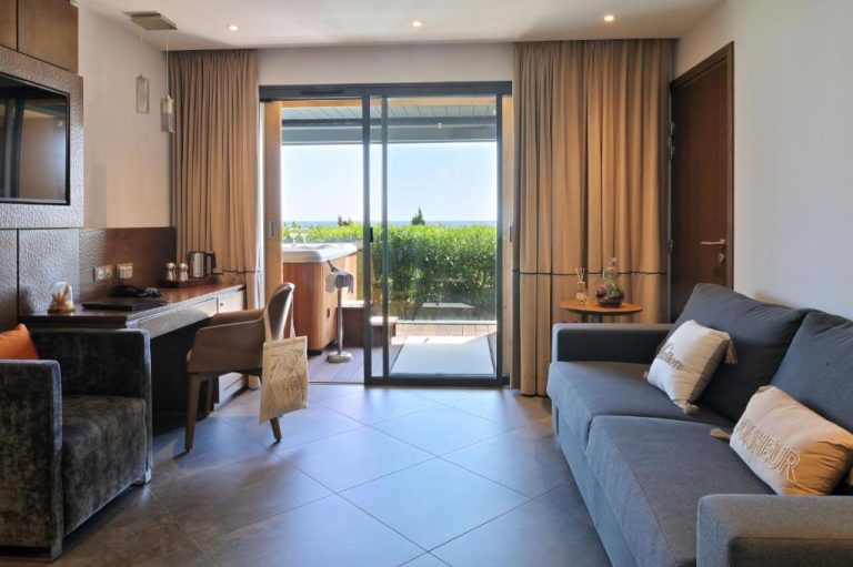 Suite con sofá, escritorio y acceso a terraza con jacuzzi en Hôtel Le Week End