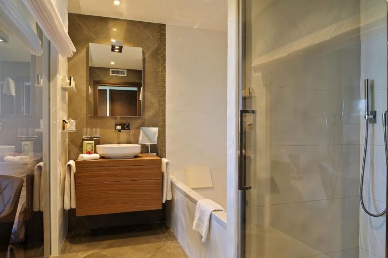 Baño moderno con ducha, bañera y lavabo del Hôtel Le Week End con acabados en madera