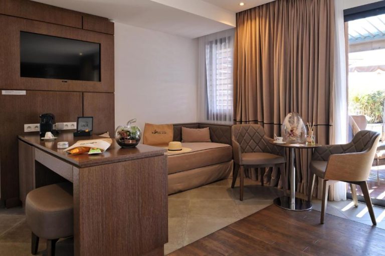 Salón moderno con sofá, mesa de trabajo y TV en habitación del Hôtel Le Week End