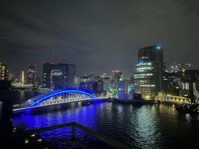 Vista nocturna del río Sumida con puente iluminado en azul desde el hotel Ulu Tokyo
