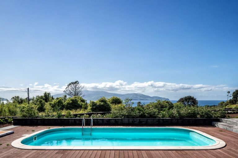 Piscina exterior con terraza de madera y vistas al mar en Alma do Pico Nature Residence, Azores