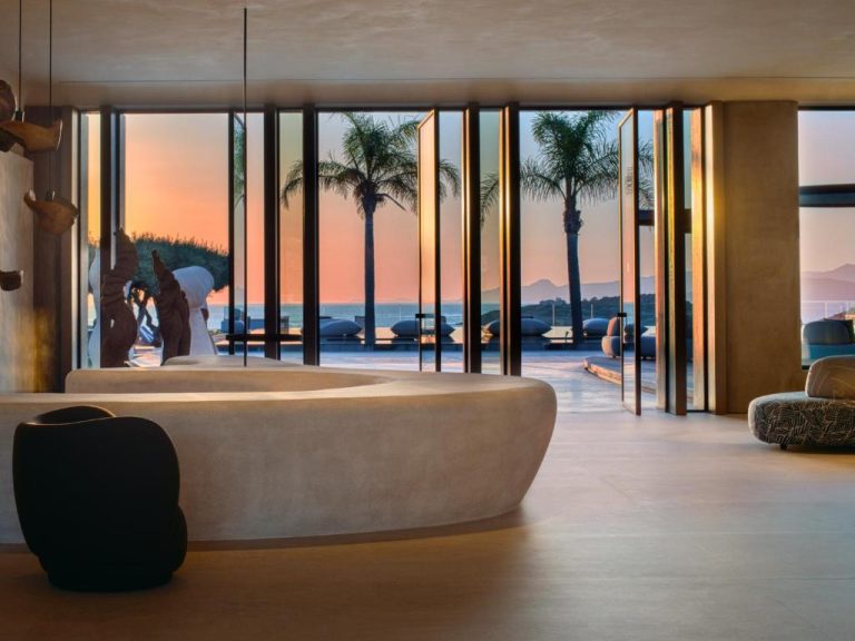 Lobby moderno del Minos Palace Resort Adults Only con vistas a la piscina y palmeras al atardecer