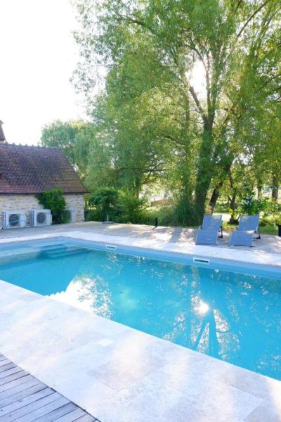 Piscina exterior con tumbonas y jardín arbolado del Moulin de Petoulle en Francia