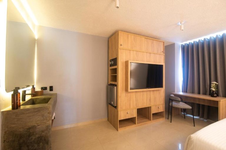 Habitación moderna con televisor empotrado en madera, escritorio y lavabo de concreto en Mood Matuna Hotel Cartagena