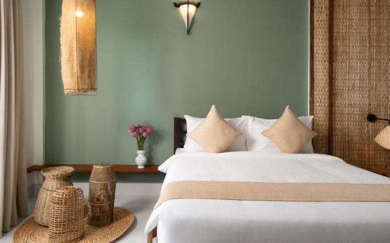 Habitación doble con pared verde salvia y decoración natural de bambú y ratán en The Jungle Hotel
