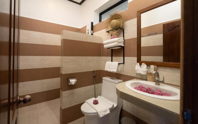 Baño completo con decoración tropical y flores de loto en The Jungle Hotel