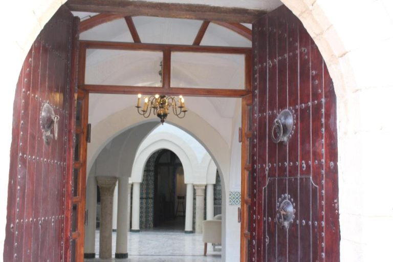 Entrada principal con puertas de madera tallada y arco árabe del Hôtel Medina