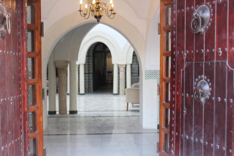 Entrada principal con puertas de madera tallada y patio interior con arcos árabes del Hôtel Medina