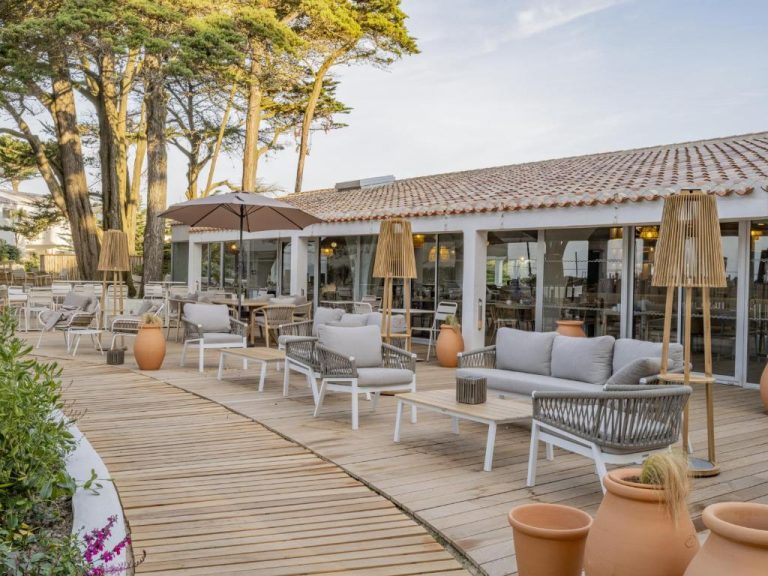 Terraza exterior con sofás y sillas del Hotel Punta Lara Noirmoutier rodeada de pinos
