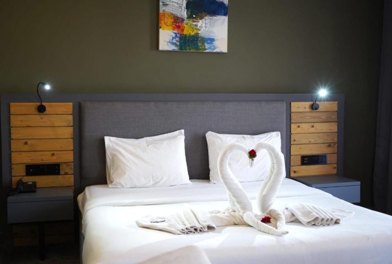 Habitación doble romántica con toallas en forma de cisnes y rosas rojas en Aitch Boutique Hotel