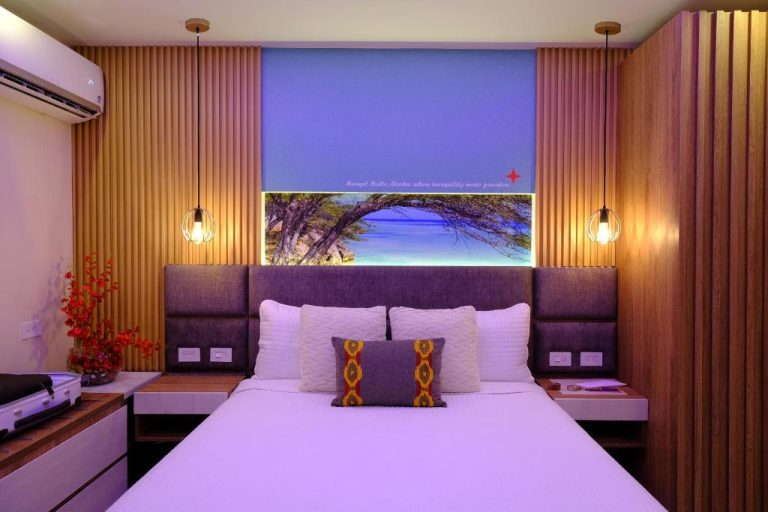 Habitación doble del Victoria City Hotel con cabecero iluminado y mural de playa tropical