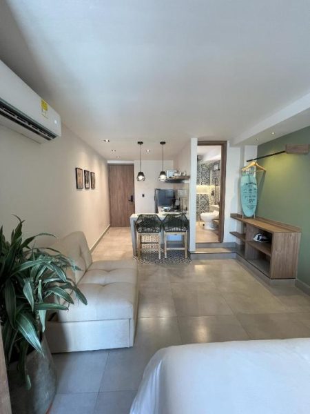 Salón con sofá blanco y cocina integrada en De la Cruz Studio Apartments con baño visible