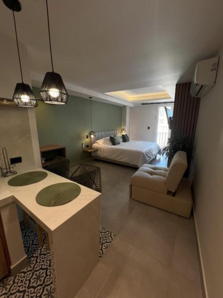 Habitación tipo estudio con cama doble, sofá y zona de comedor en De la Cruz Studio Apartments