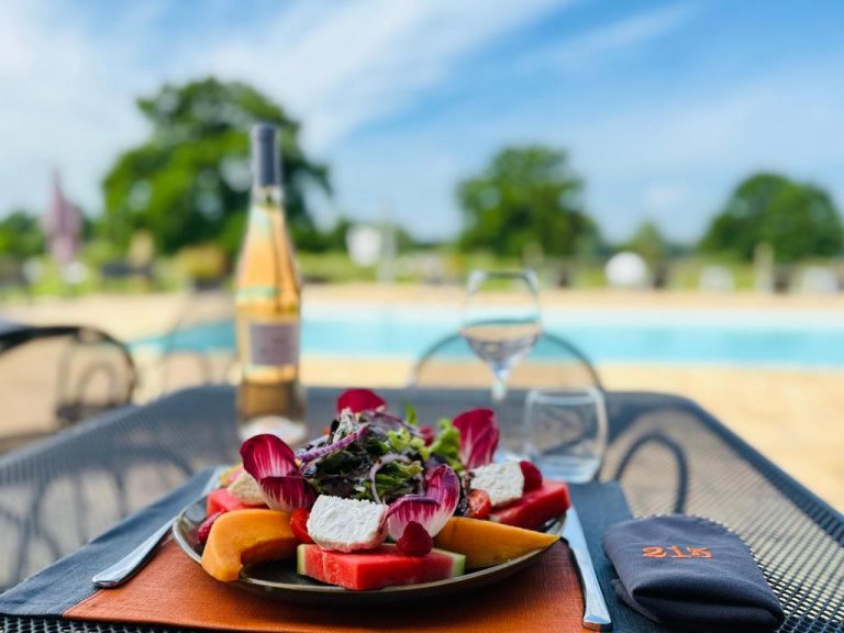 Ensalada de frutas y vino rosado junto a la piscina exterior del Hotel Le Noirlac en verano