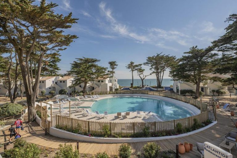 Piscina exterior circular con tumbonas y vistas al mar en Hotel Punta Lara Noirmoutier