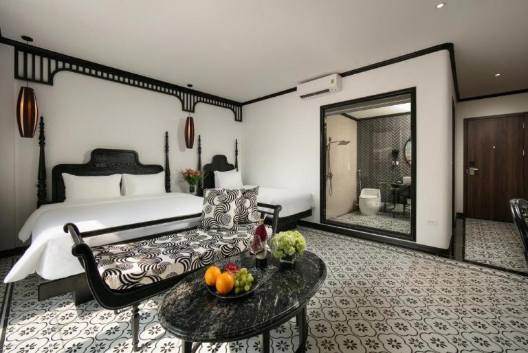 Habitación deluxe en blanco y negro con cama doble y baño abierto en Hanoi Le Chateau Hotel & Spa