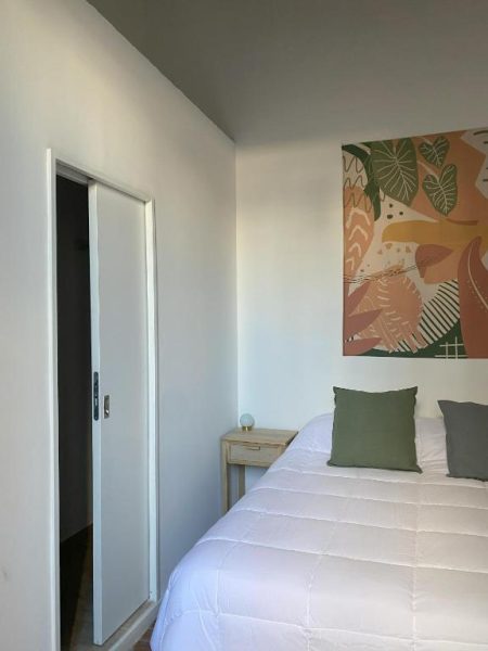 Habitación doble con cama blanca y decoración tropical en Casa Rebelión