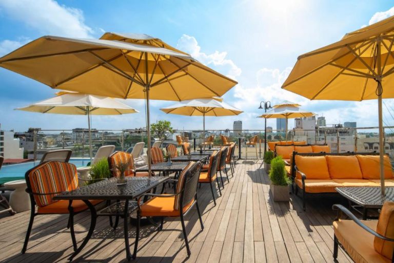 Terraza bar con sombrillas amarillas y vistas panorámicas de la ciudad en Anatole Hotel Hanoi