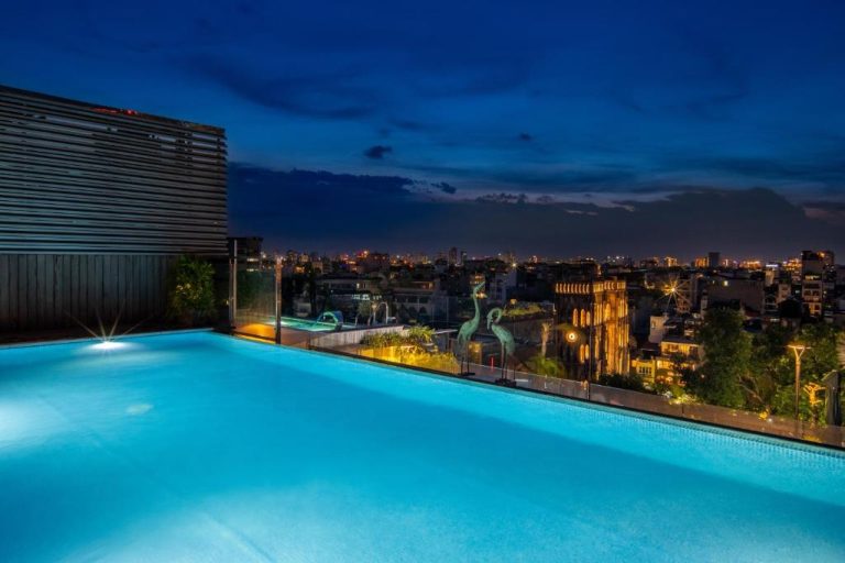 Piscina infinita en la azotea del Anatole Hotel Hanoi con vistas panorámicas de la ciudad de noche