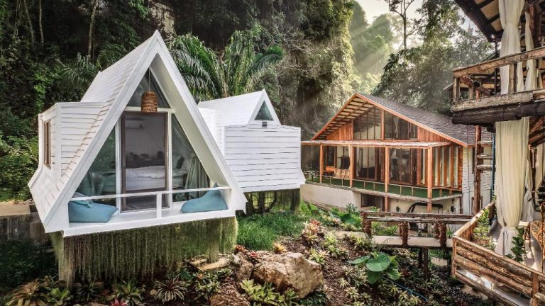 Cabañas tipo A-frame blancas y villa de madera rodeadas de selva tropical en Voasis Valley Krabi Natural Resort
