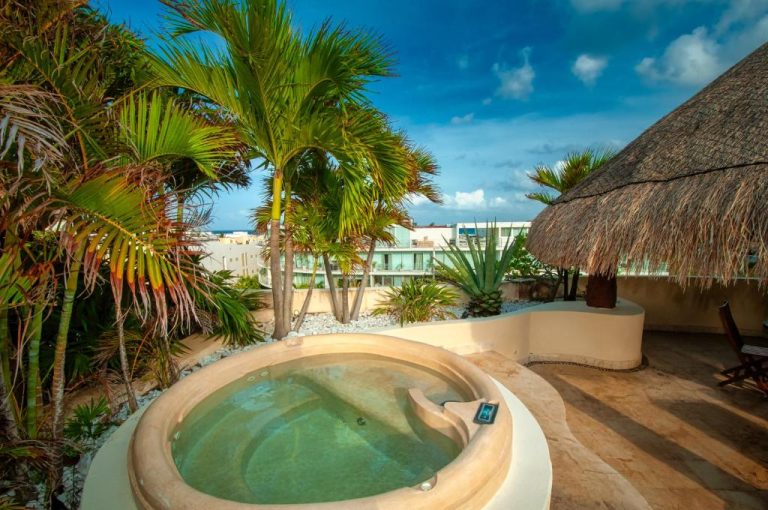 Jacuzzi privado en terraza exterior con palmeras tropicales del Porto Playa Condo Hotel and Beach Club
