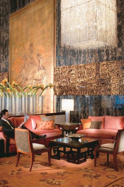 Elegante lobby lounge con sofás naranjas y gran lámpara de cristal en Mandarin Oriental Hong Kong