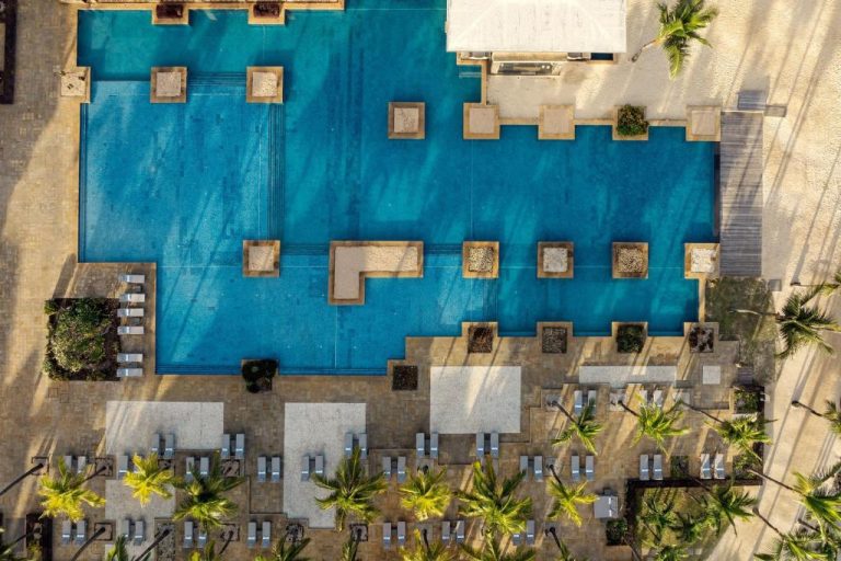 Vista aérea de la piscina exterior del The Westin Turtle Bay Resort & Spa en Mauricio con tumbonas y palmeras