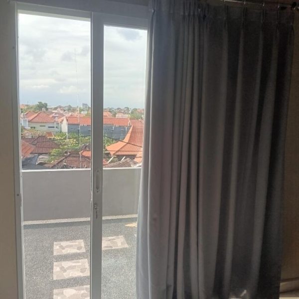 Balcón con puerta corredera y vistas a los tejados del barrio en 9 Residence's Seminyak