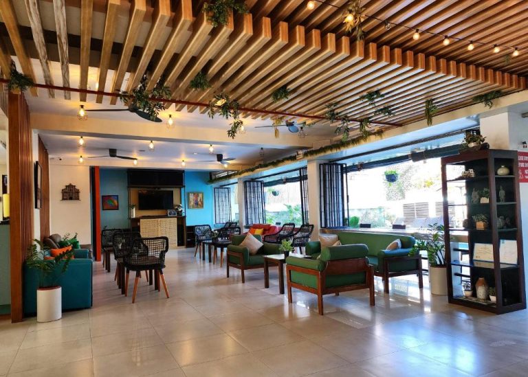 Lobby tropical del Sea Cocoon Hotel con sillones verdes, techo de madera y decoración de plantas naturales