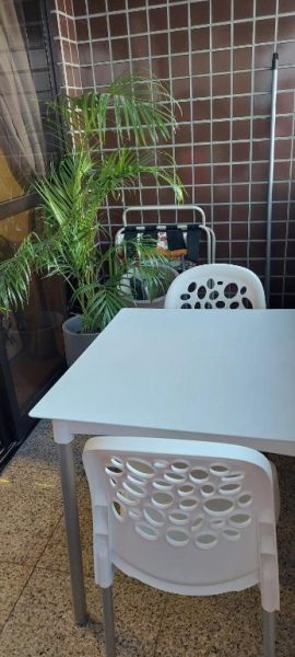 Terraza exterior con mesa y sillas blancas de plástico y planta tropical en apartamento Fortaleza 703-713