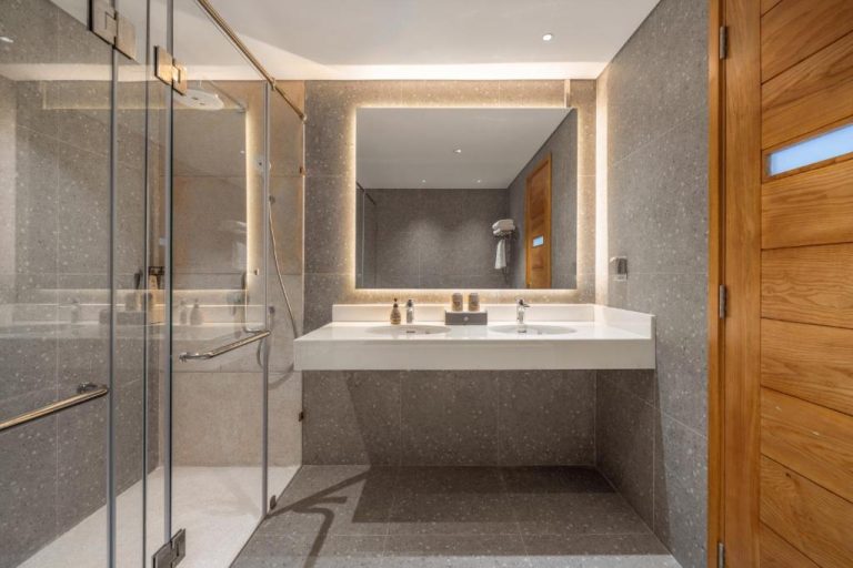 Baño moderno con doble lavabo, ducha de cristal e iluminación LED en Vernal Hotel Da Nang